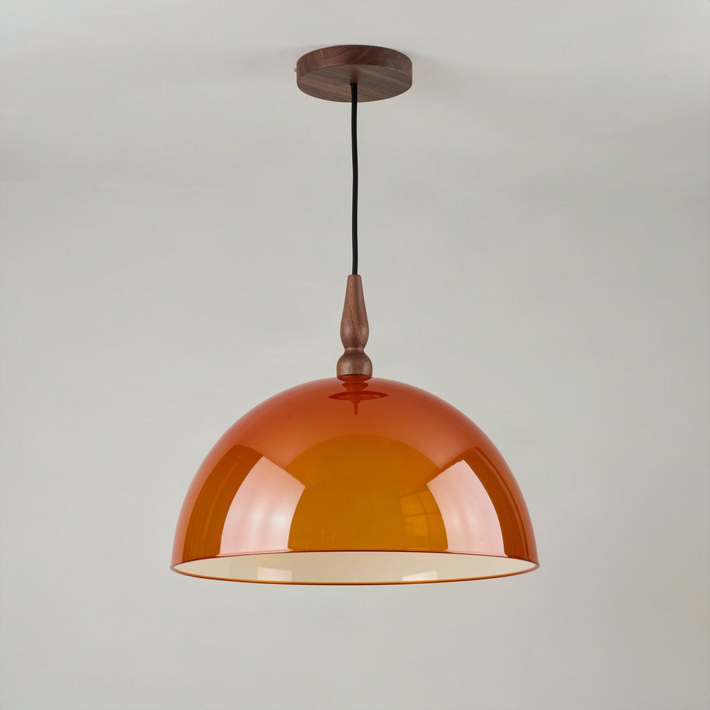 Amber acrylic dome pendant light with walnut finial hanging against a plain wall