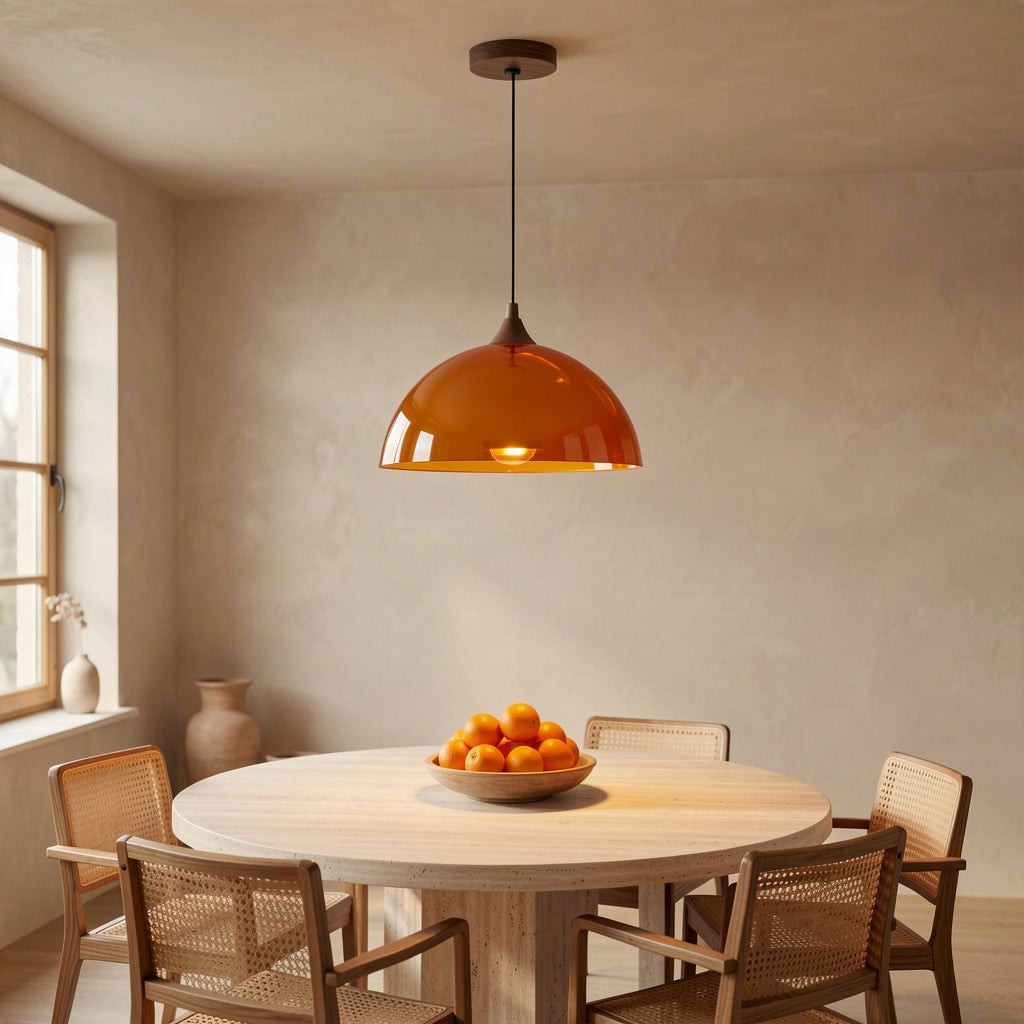 Amber dome pendant lit above a round dining table in a plaster-walled room