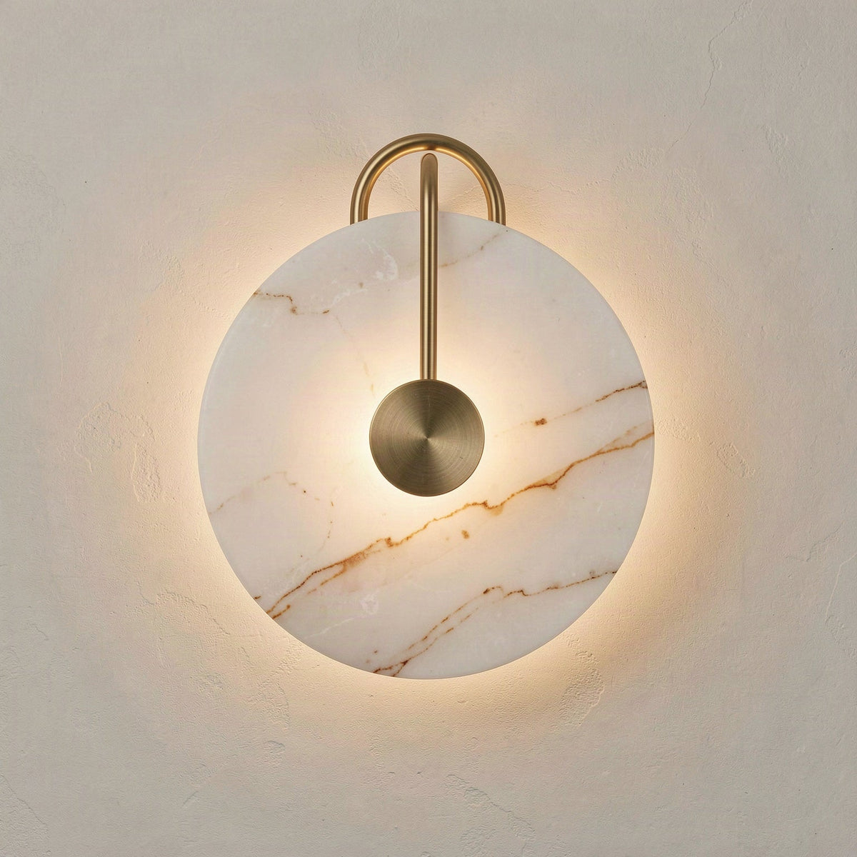 Round artificial marble disc wall light lit from behind, with a gold rod arching over the face to a centre boss