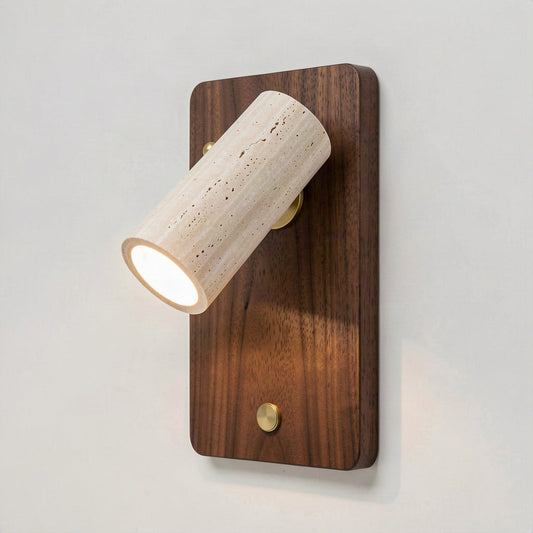 Travertine cylinder spot wall light on a walnut backplate, beam angled down a pale wall