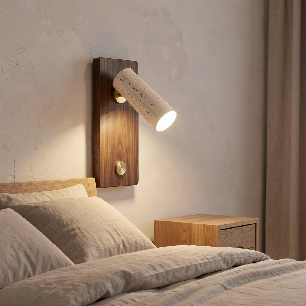 The travertine spot wall light mounted above a bedside table in a warmly lit bedroom