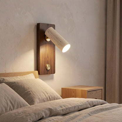 The travertine spot wall light mounted above a bedside table in a warmly lit bedroom