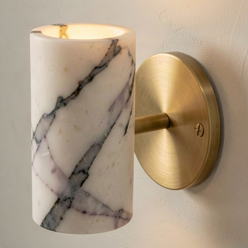 Close-up of the marble veining and the brushed brass wall plate with its fixing screw