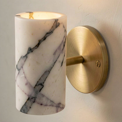 Close-up of the marble veining and the brushed brass wall plate with its fixing screw