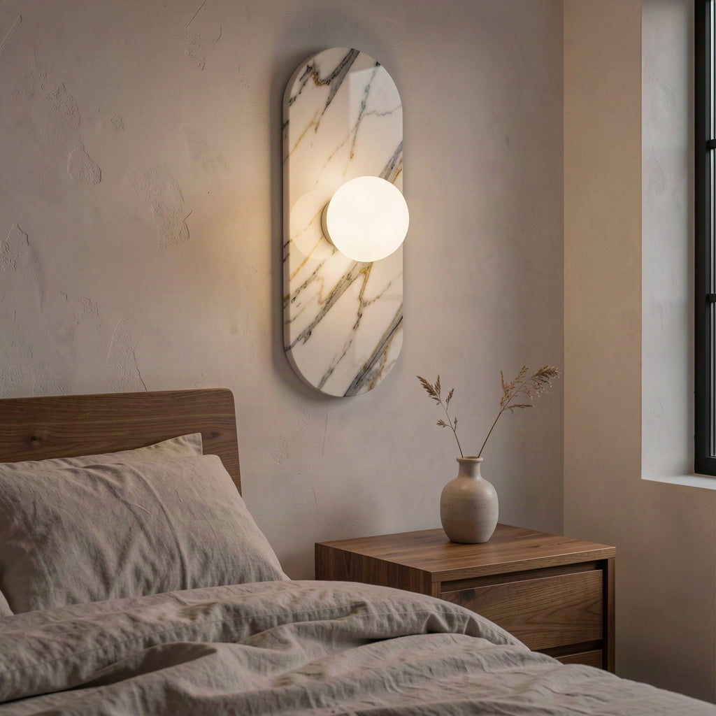 Oval marble wall light mounted beside a bed in a warmly lit bedroom