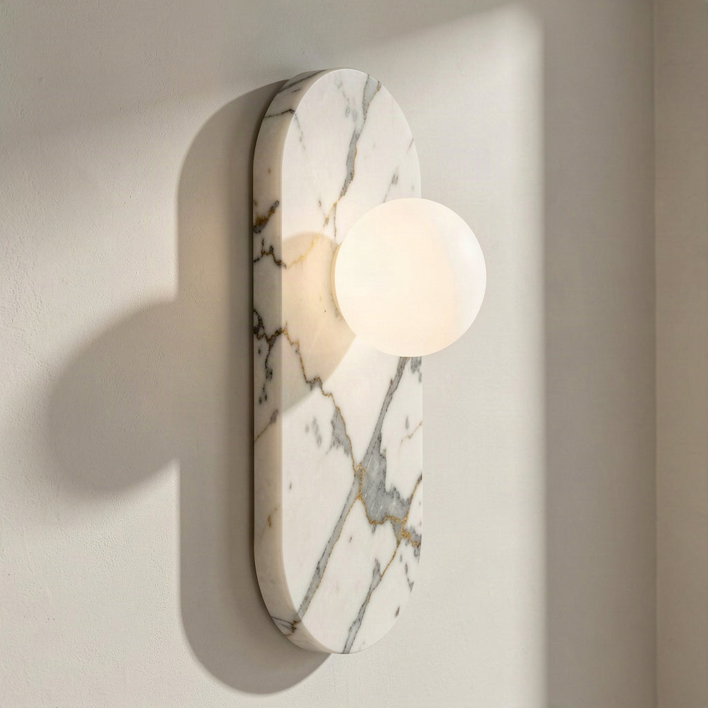 Angled view of the oval marble wall light showing its slim profile and glass globe