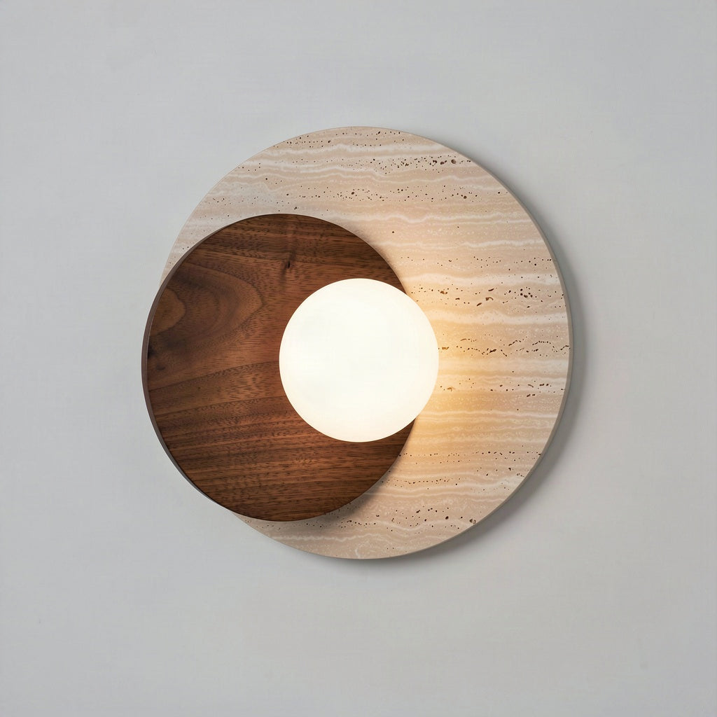 Travertine and walnut disc wall light with an opal glass globe, lit against a pale wall