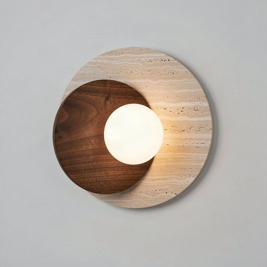 Travertine and walnut disc wall light with an opal glass globe, lit against a pale wall