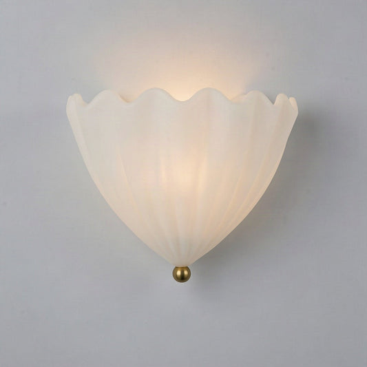 Shell shaped pleated glass wall light in cream, mounted on a plain wall