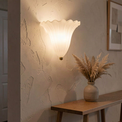 Shell glass wall light lit above a console table, washing light up the wall