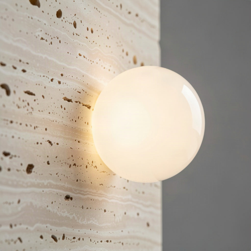 Close-up of an opal glass globe half-sunk into the pitted travertine surface