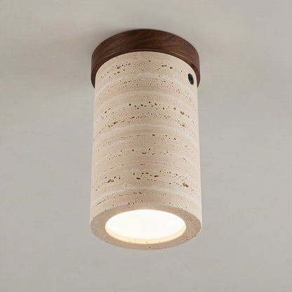 Travertine cylinder ceiling light with a walnut wood cap, lit and surface mounted on a plain ceiling