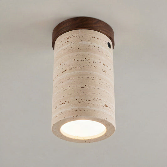Travertine cylinder ceiling light with a walnut wood cap, lit and surface mounted on a plain ceiling