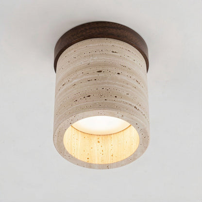 Angled view of the travertine drum, the walnut cap and the lit diffuser in its open base