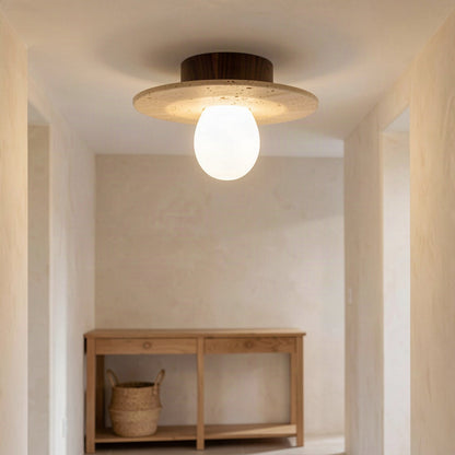 Travertine disc ceiling light lit in a hallway above a wooden console