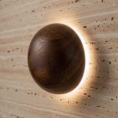 Close-up of the turned wooden sphere with warm light escaping the gap around its base