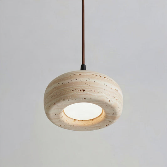Travertine donut pendant light hanging on a cord against a pale wall
