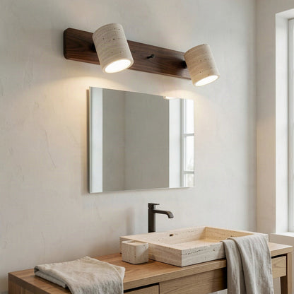 Two-head travertine wall light lit above a mirror in a plain bathroom