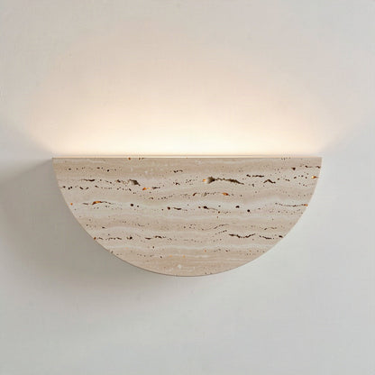 Travertine half-moon wall light washing warm light up a pale wall