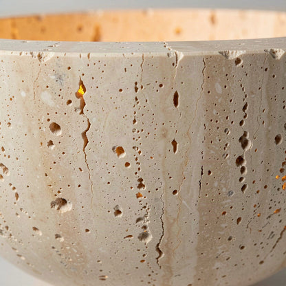 Close detail of the pitted, porous travertine surface of the sconce