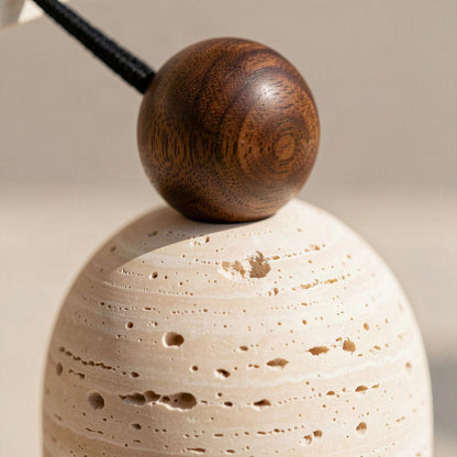 Close-up of the turned walnut bead sitting on the open-pored travertine body
